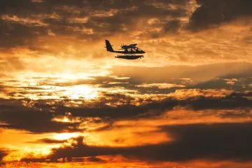 North Jetty: Seaplane  Flies Through the Sunset