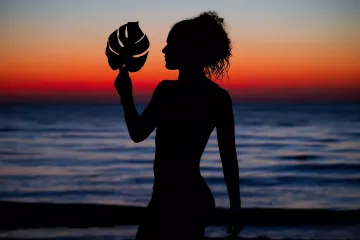 Turtle Beach: Silhouetted Woman Holds a Leaf with a Red Afterglow