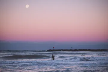 Venice, Florida: Surfer Enters the Water at Sunrise with the Moonset Behind