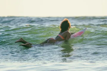 Surfer Girl Paddles Out Against Waves